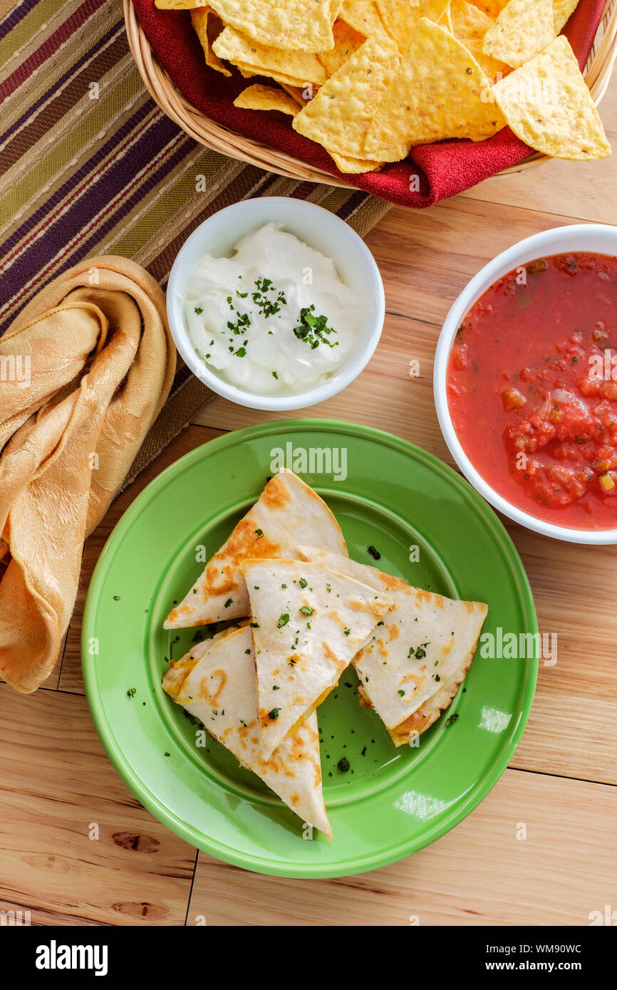 Cheesy chicken quesadilla cut into triangles with tortilla chips salsa