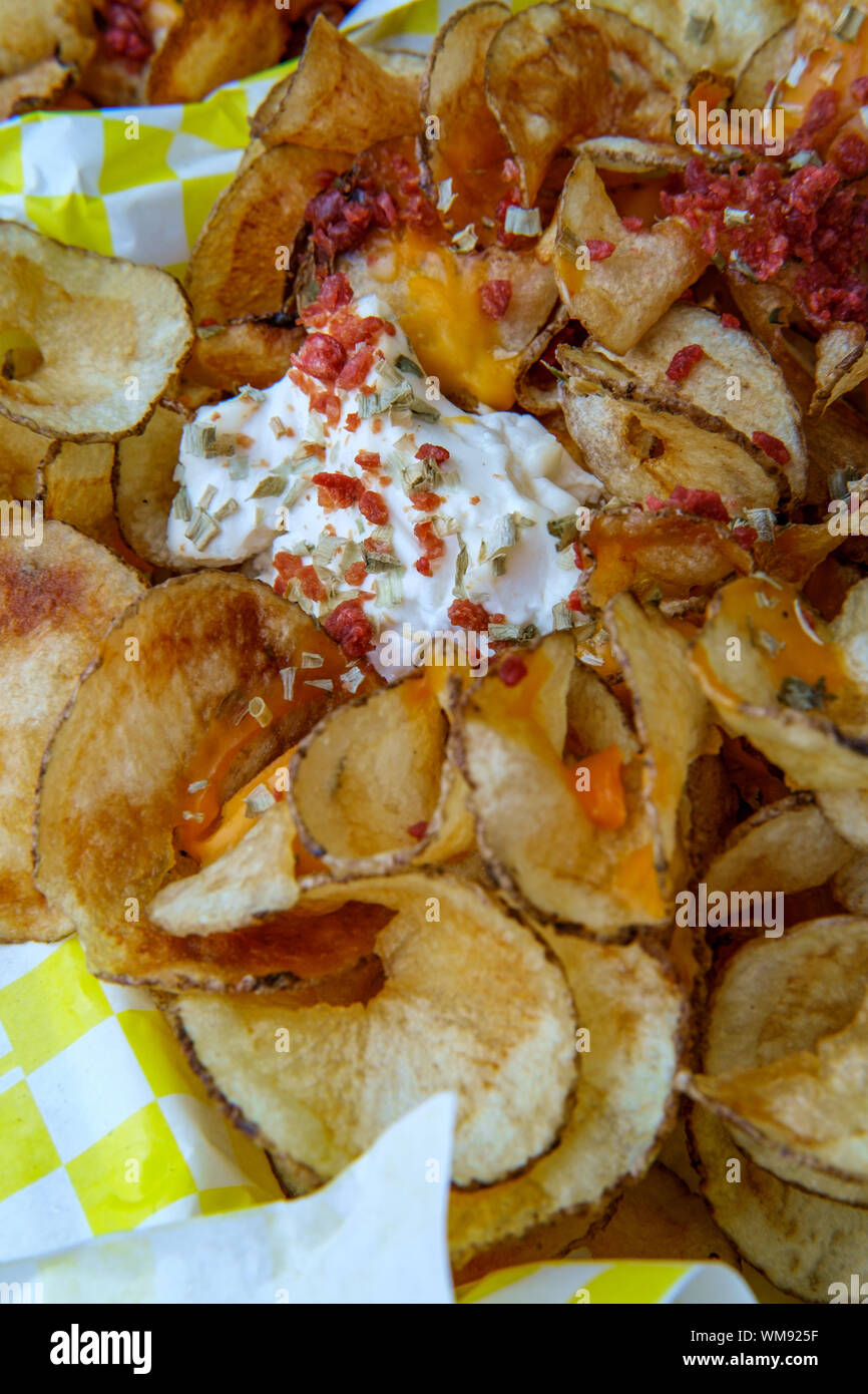 Carnival style ribbon cut potato chip fries with bacon bits and sour cream Stock Photo