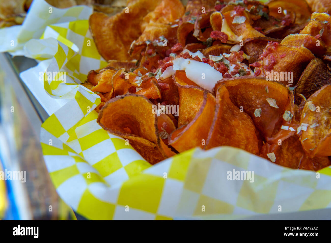 Carnival style ribbon cut potato chip fries with bacon bits and sour cream Stock Photo