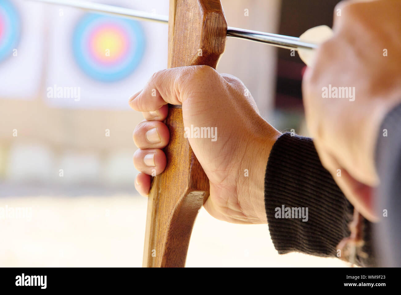 Archer holds his bow aiming at a target Stock Photo