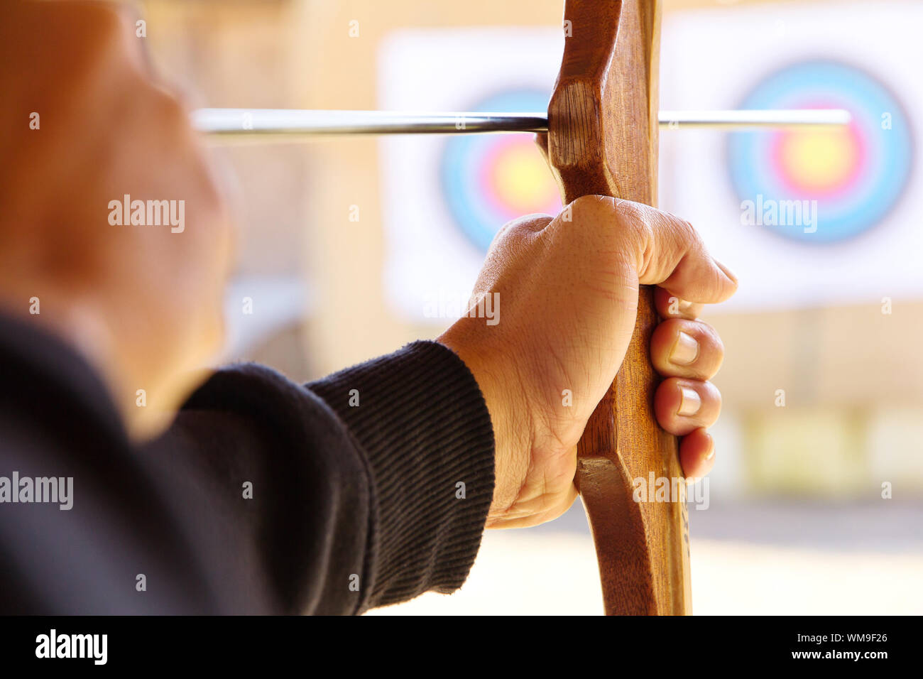 Archer holds his bow aiming at a target Stock Photo