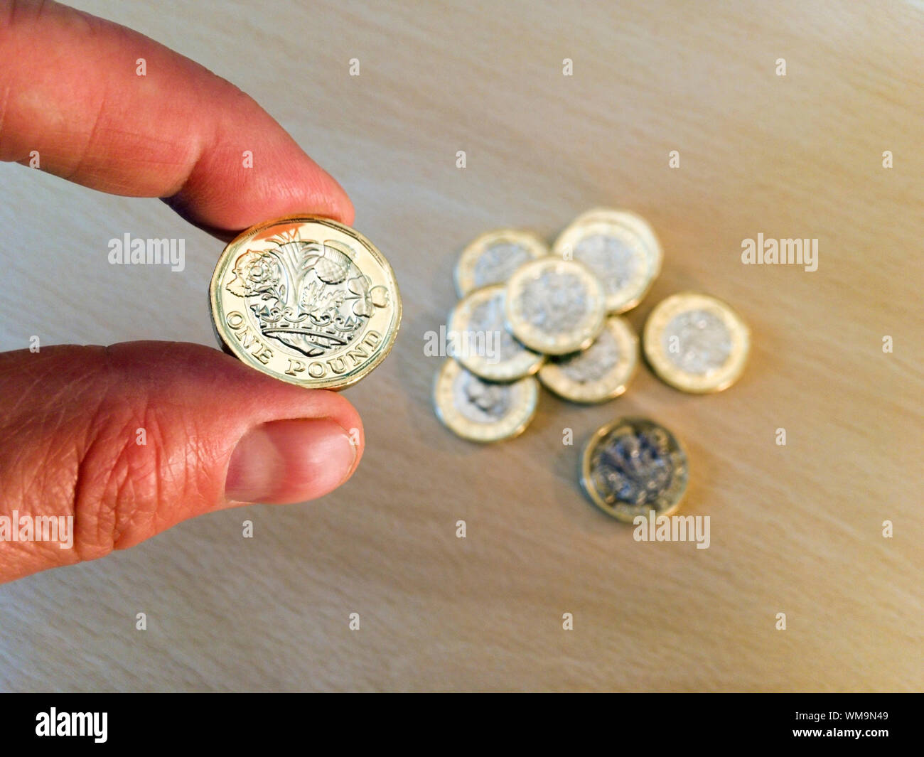 Cropped Hand Of Person Holding One Pound Coin Over Table Stock Photo