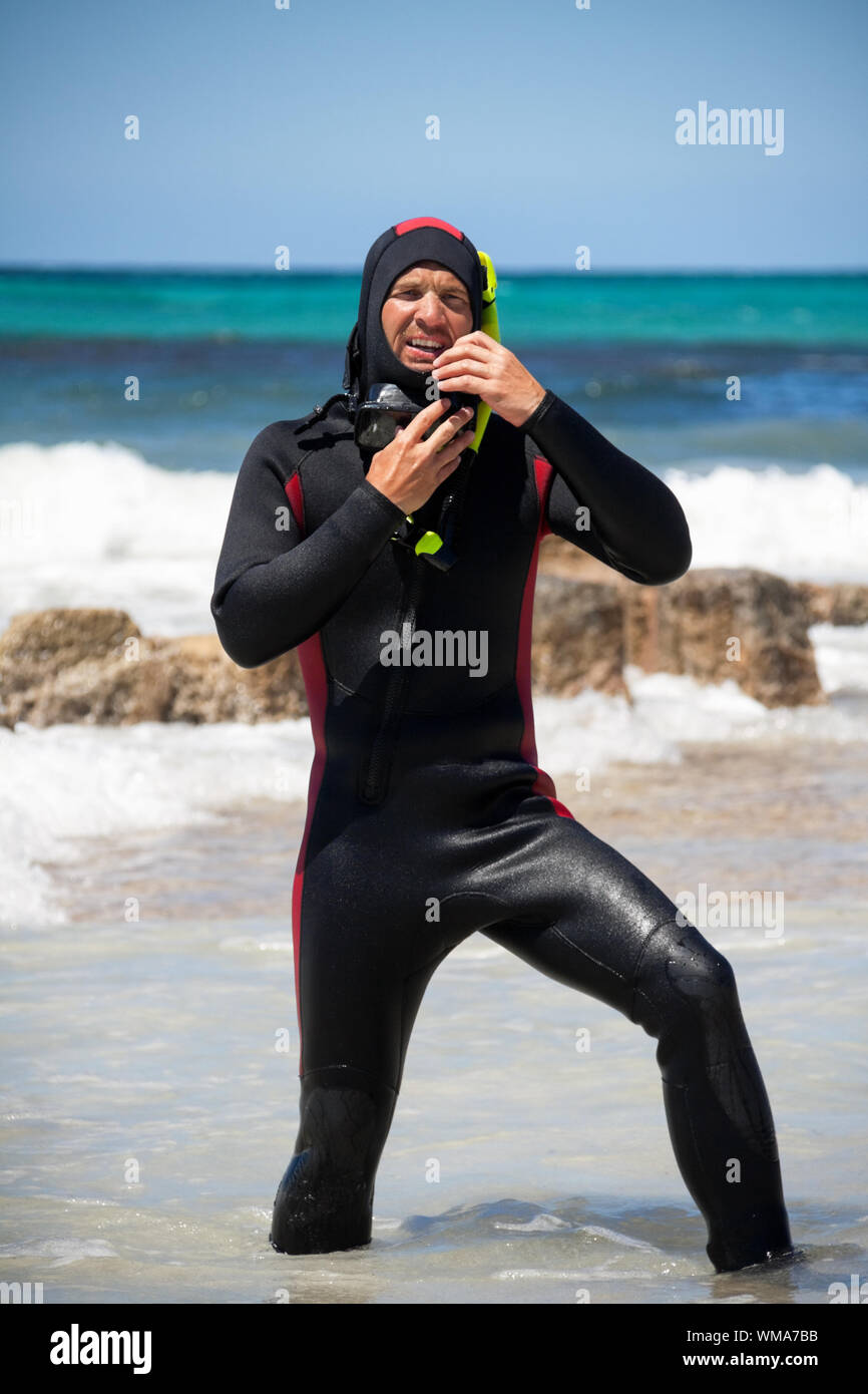 male diver with diving suit snorkel mask fins on the beach in Summer Stock Photo