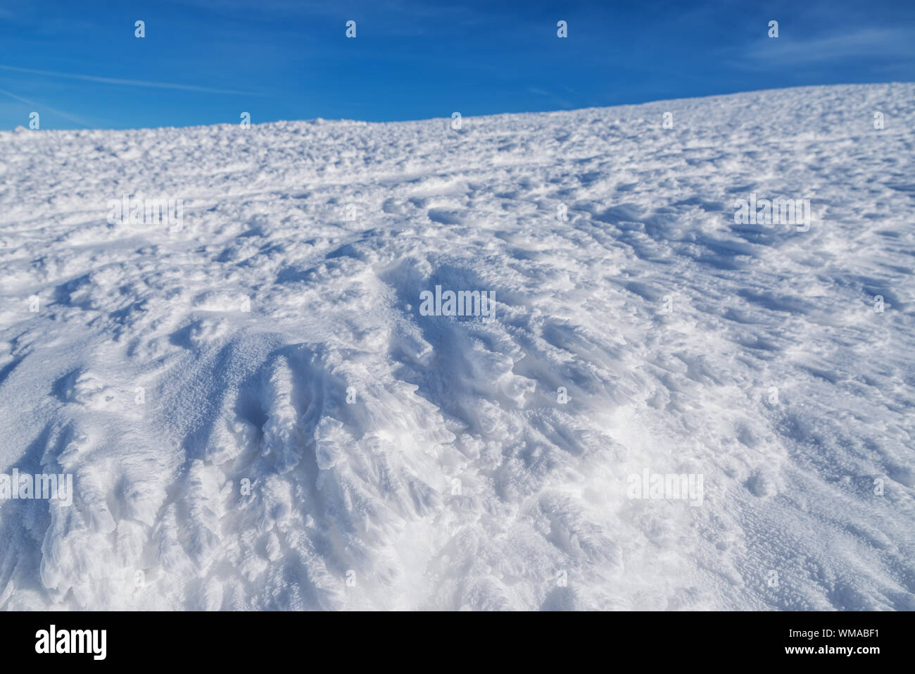 Fresh sparkling snow cover on mountain tops. Blue sky at the background. Stock Photo