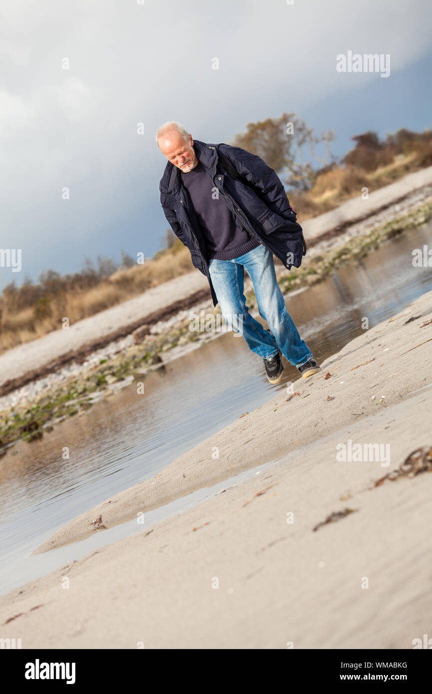 Elderly energetic man running along a beach Stock Photo