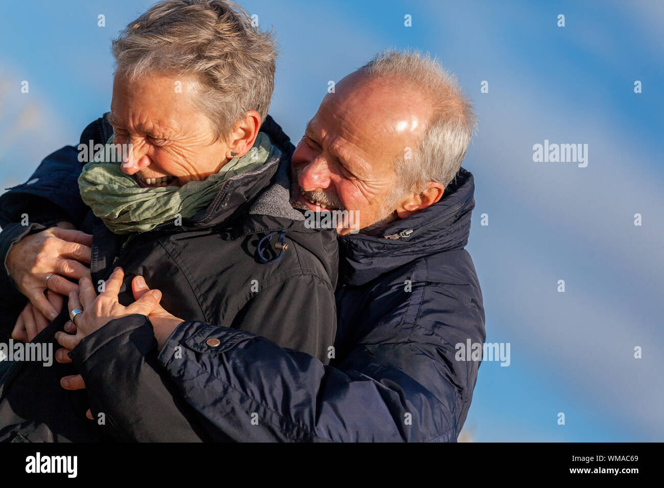 Elderly couple embracing and celebrating the sun Stock Photo