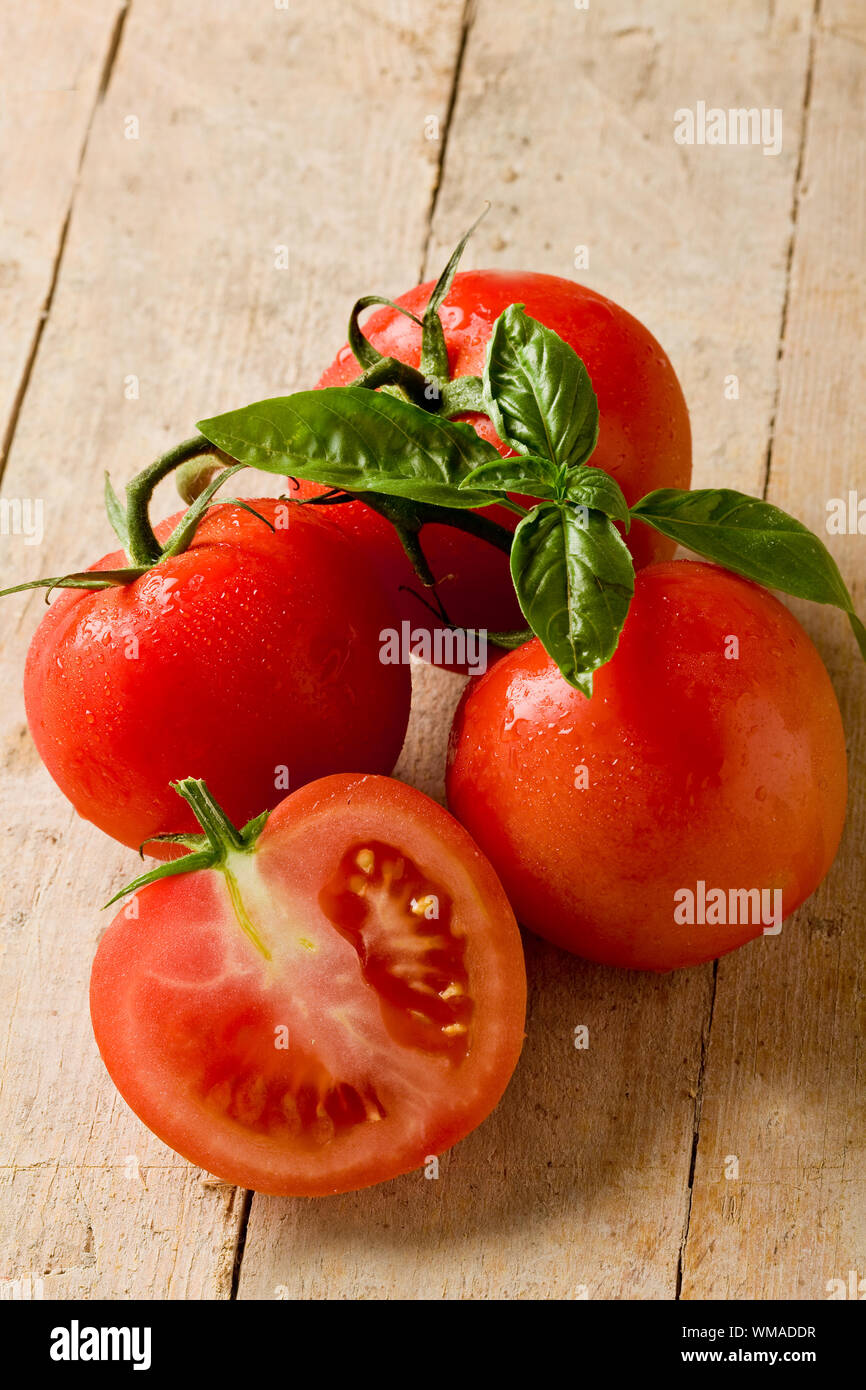 photo of delicious fresh tomatoes with basil leaves on wooden table ...