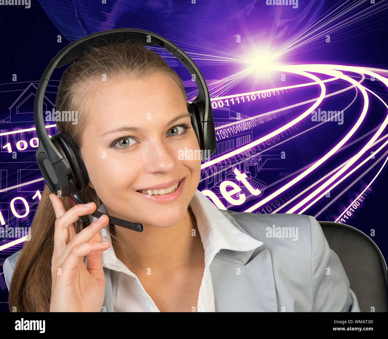 Closeup of businesswoman in headset, her hand on microphone, looking at camera, smiling. Wire-frame building with light as backfrop Stock Photo