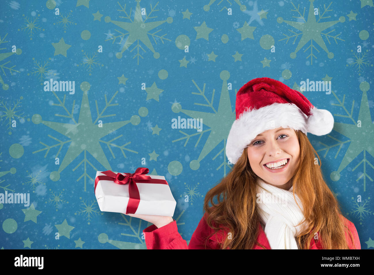 Festive redhead holding a gift against snowflake wallpaper pattern ...
