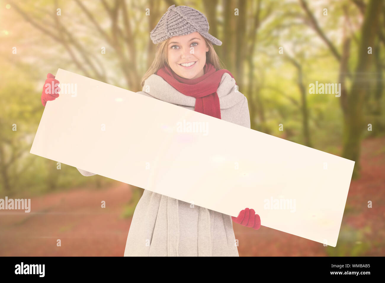 Happy blonde in winter clothes showing card against peaceful autumn scene in forest Stock Photo ...
