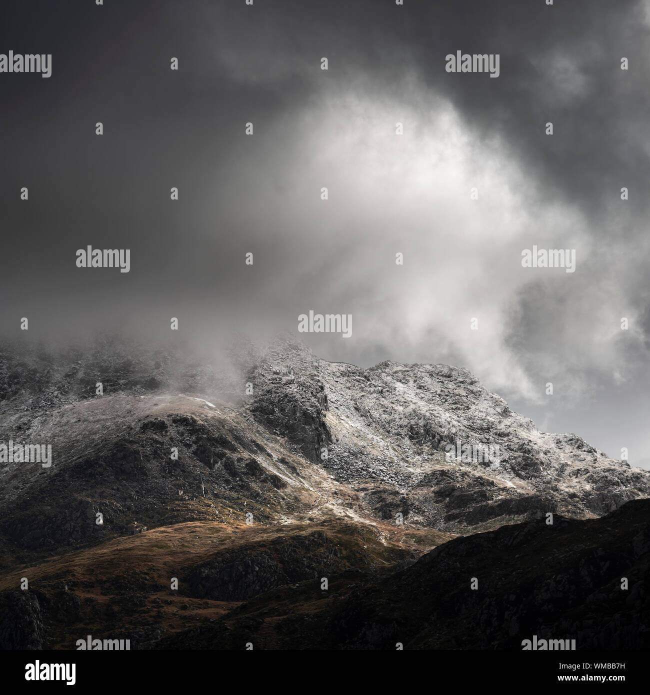 Stunning moody dramatic Winter landscape image of snowcapped Tryfan mountain in Snowdonia during