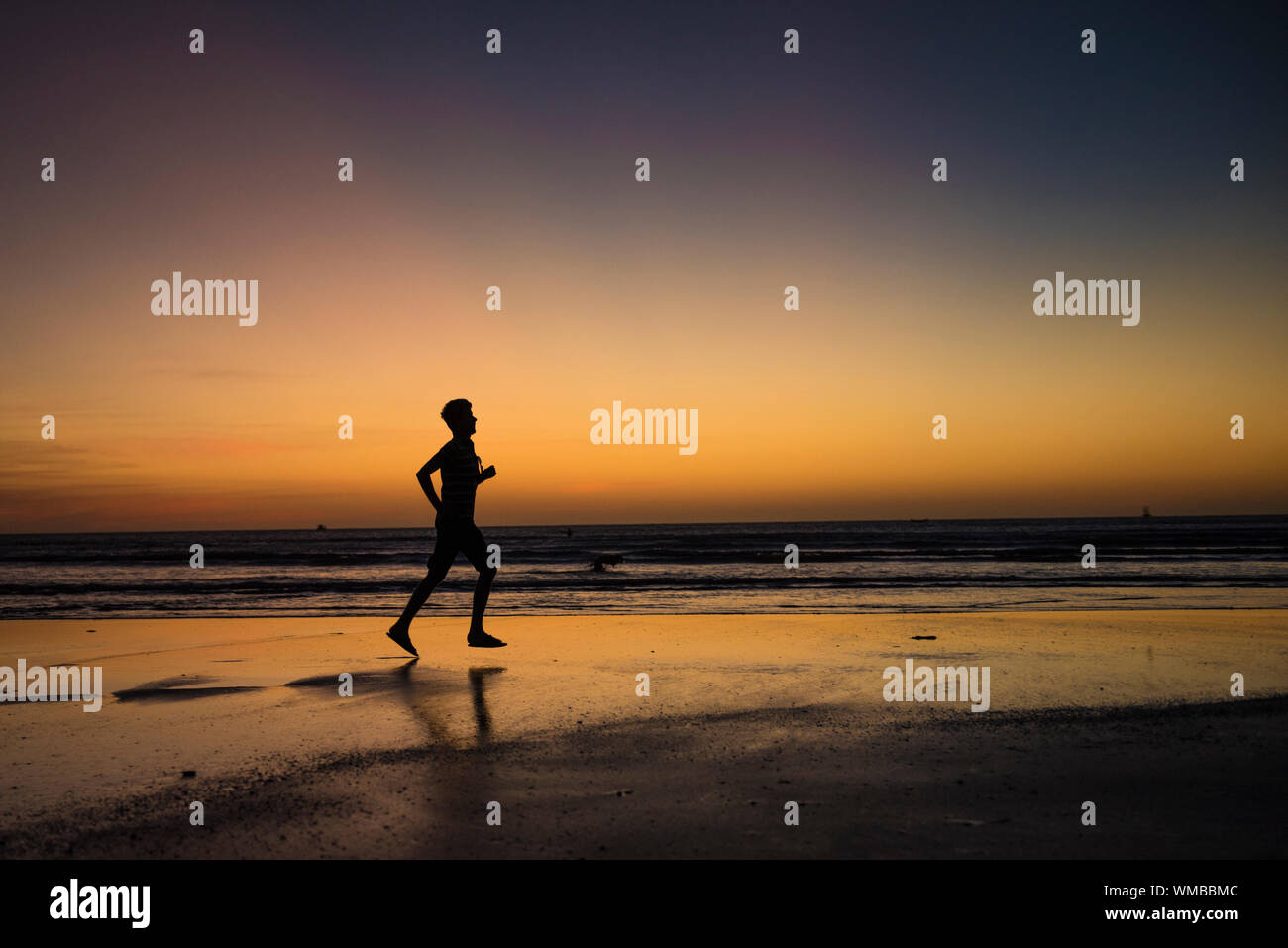 Silhouette of man running on beach at sunset hi-res stock photography ...