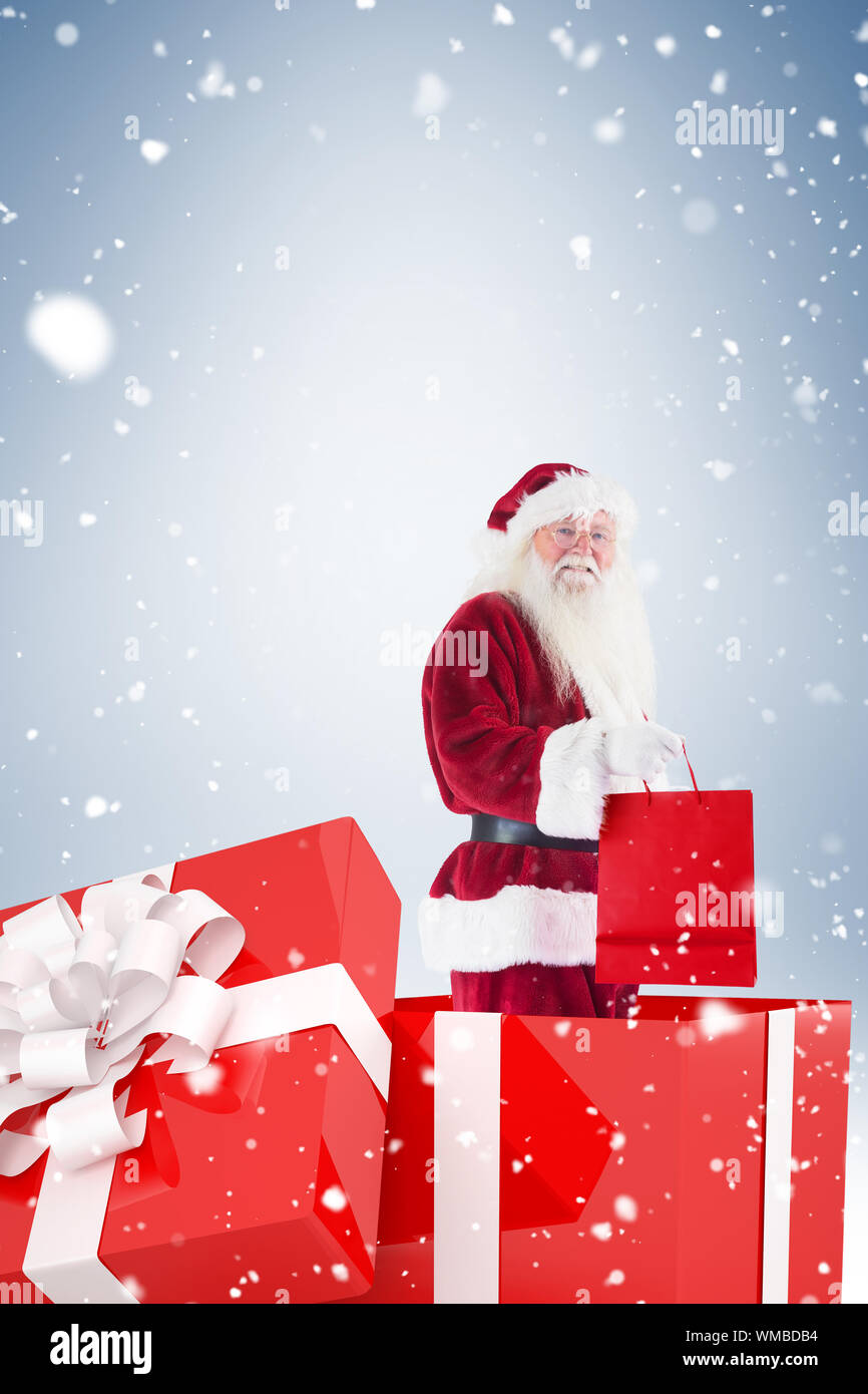 Santa standing in large gift against blue vignette Stock Photo - Alamy