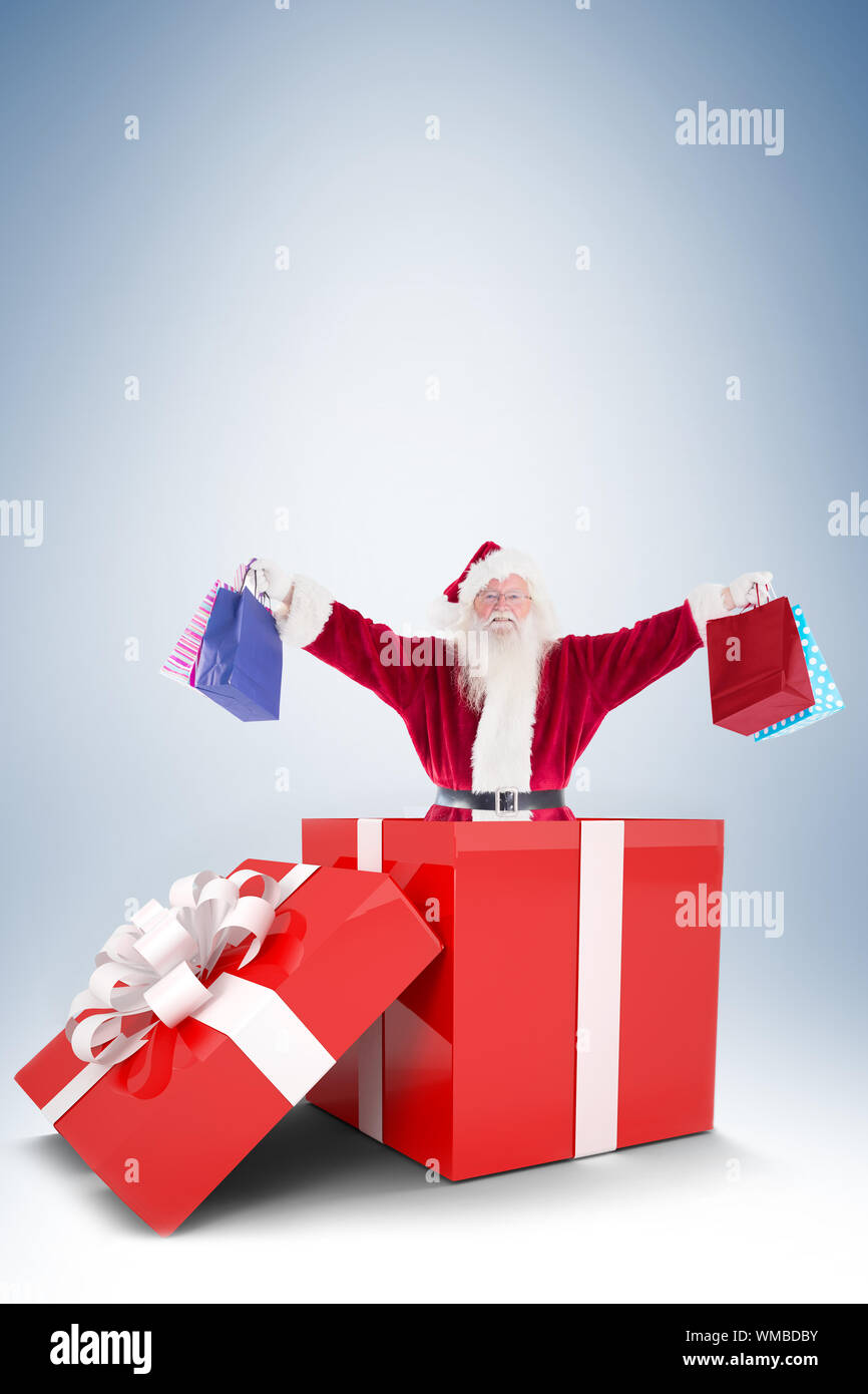 Santa standing in large gift against blue vignette Stock Photo - Alamy