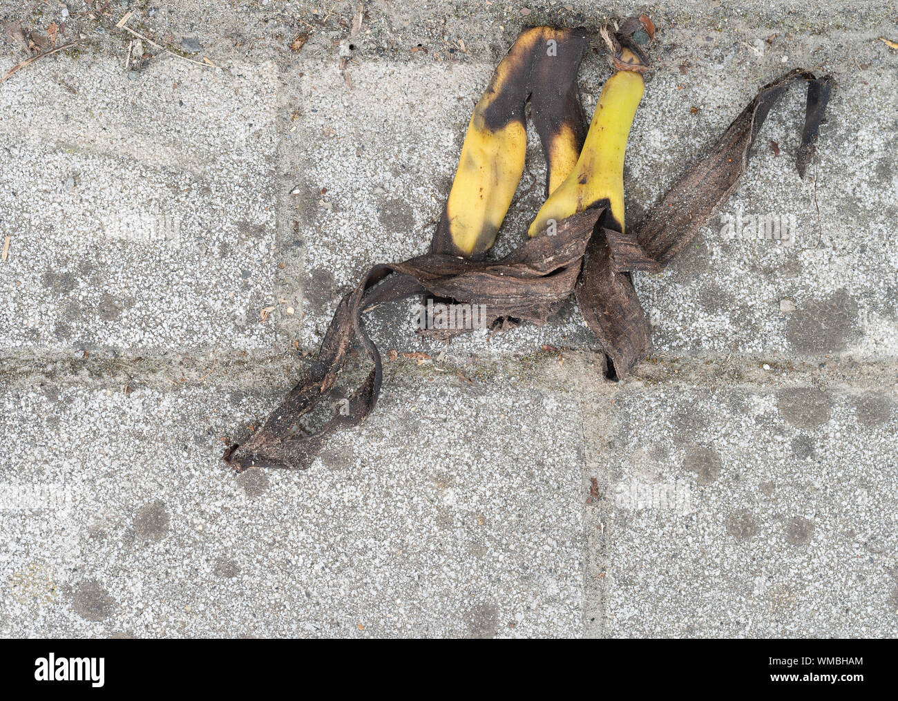 Old discarded banana skin on grubby pavement, sidewalk. Not biodegrading quickly. Stock Photo