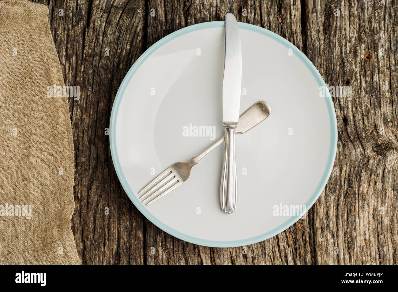 Plate and cutlery on rustic wooden table with canvas. Flat lay. Stock Photo