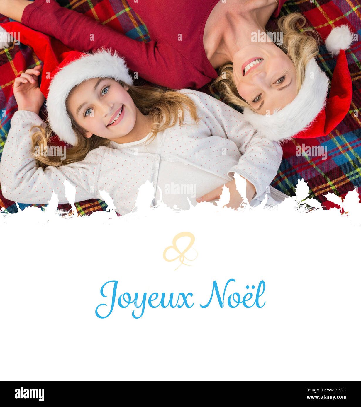 Festive mother and daughter smiling at camera on blanket against Christmas greeting card Stock ...
