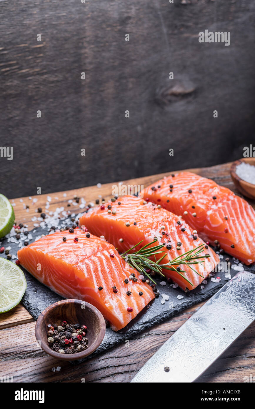 Fresh salmon fillets on black cutting board with herbs and spices Stock ...