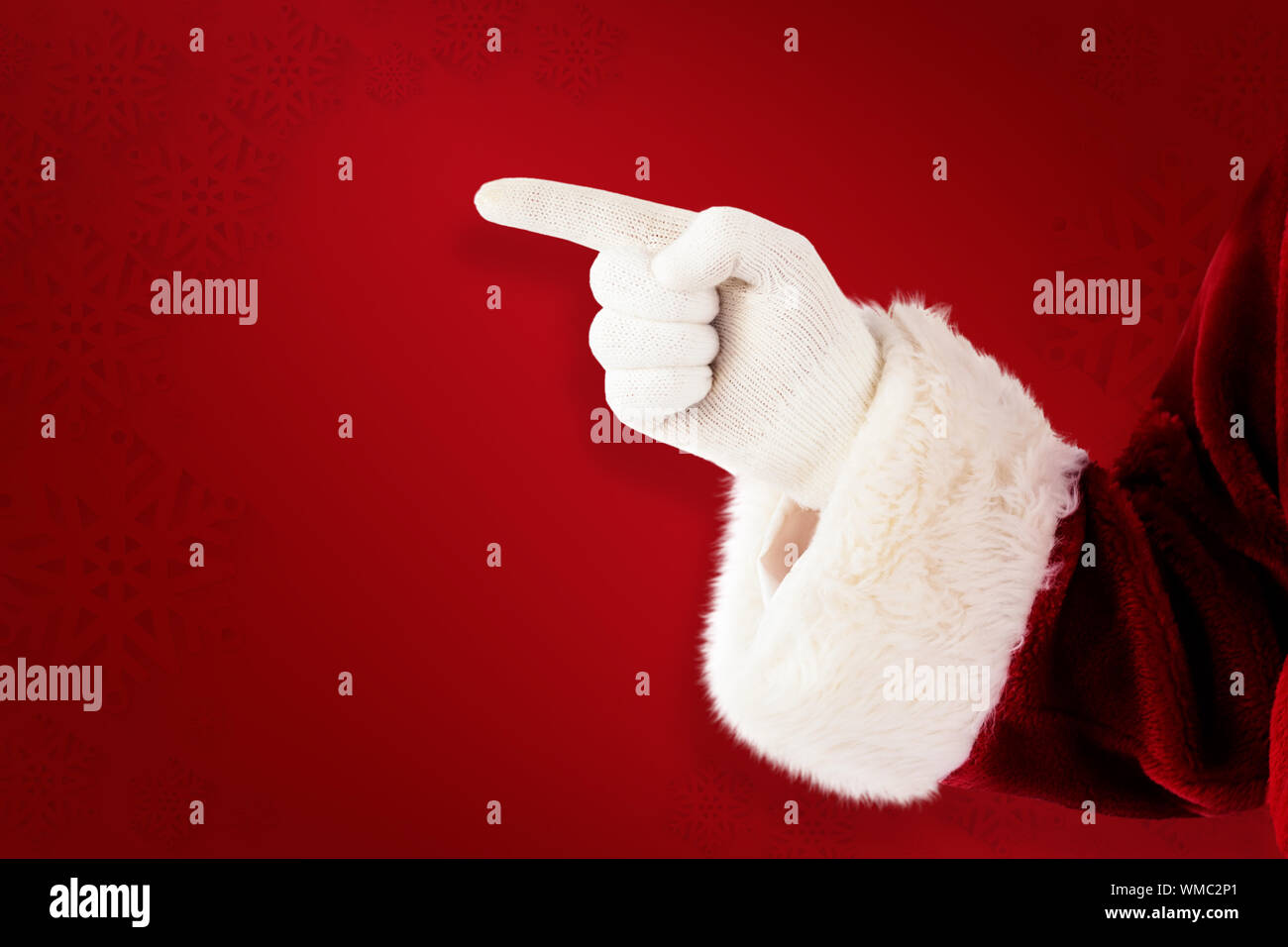 Santa Claus points at something against red background Stock Photo