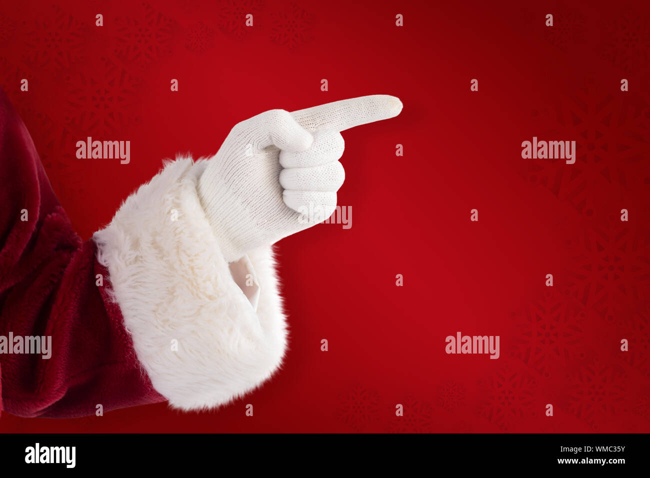 Santa Claus points at something against red background Stock Photo