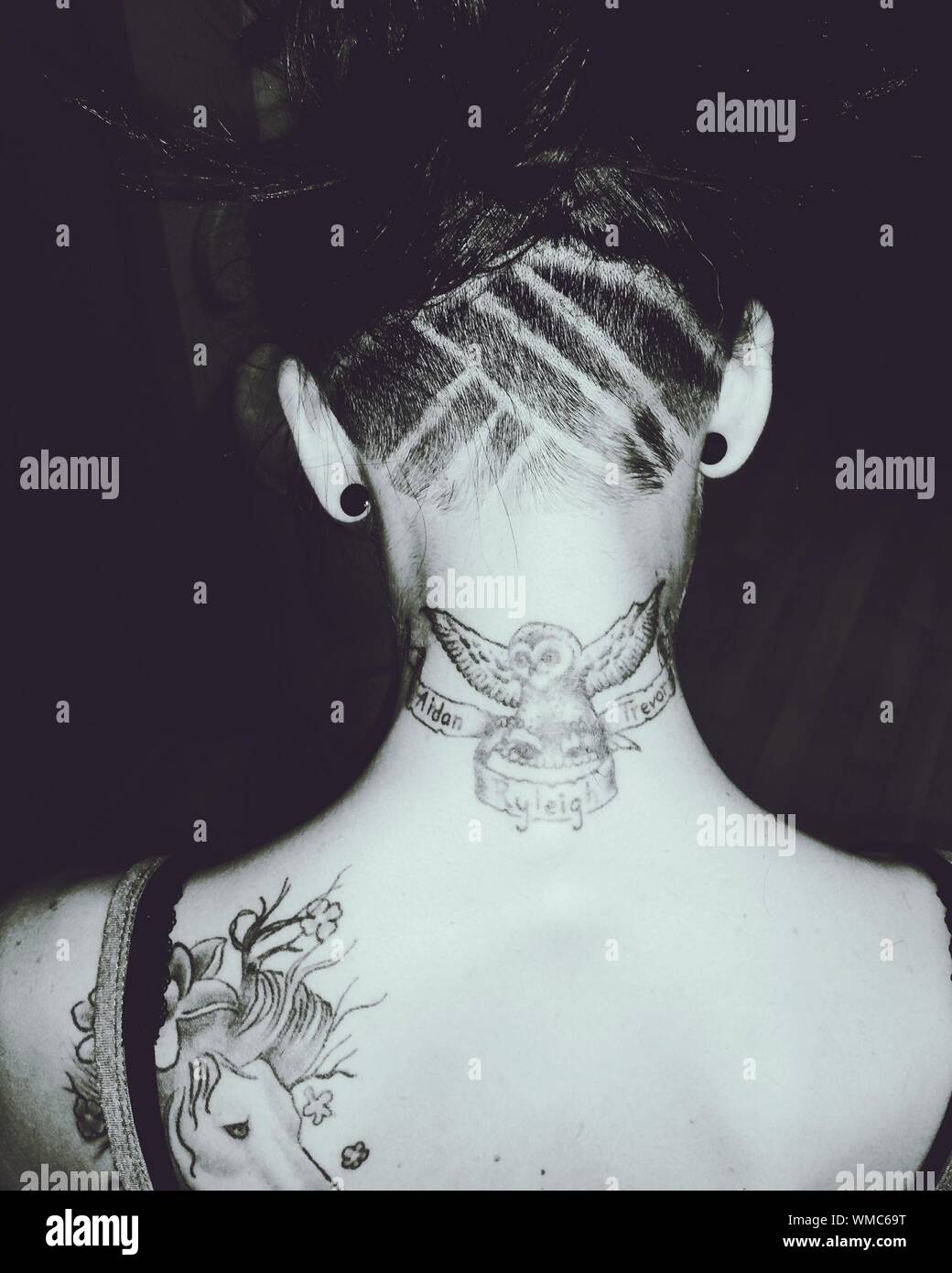 Rear View Of Woman With Half Shaved Hairstyle And Tattoos Stock
