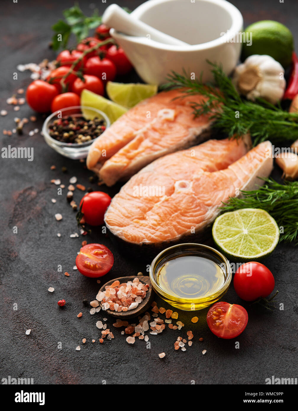 Raw salmon steaks and ingredients on a black slate board Stock Photo ...