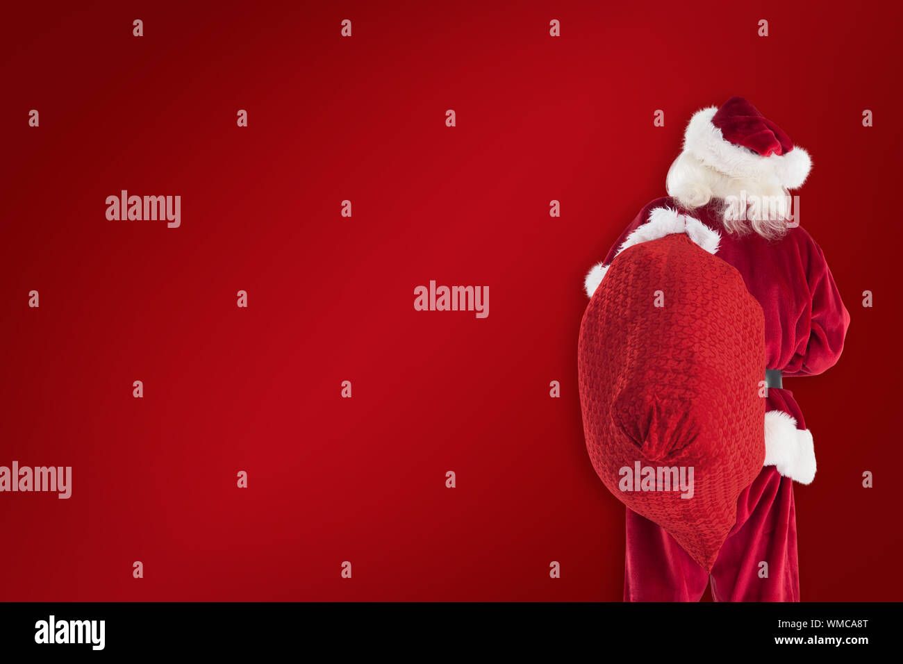 Santa is holding his bag in one hand against red background Stock Photo ...