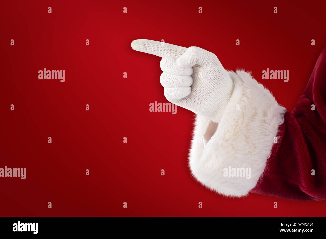 Santa Claus points at something against red background Stock Photo