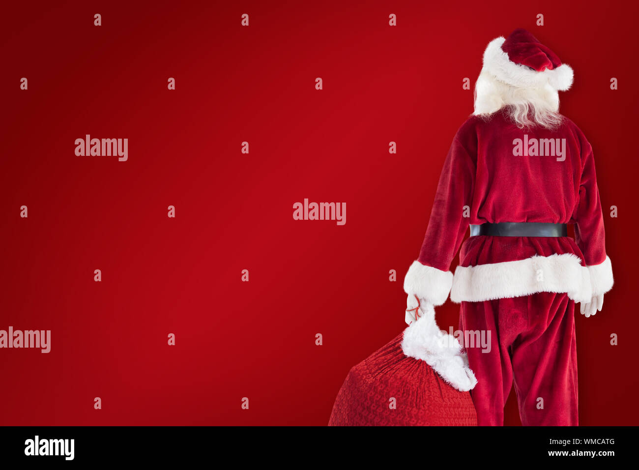 Santa carrying sack of gifts against red background Stock Photo - Alamy
