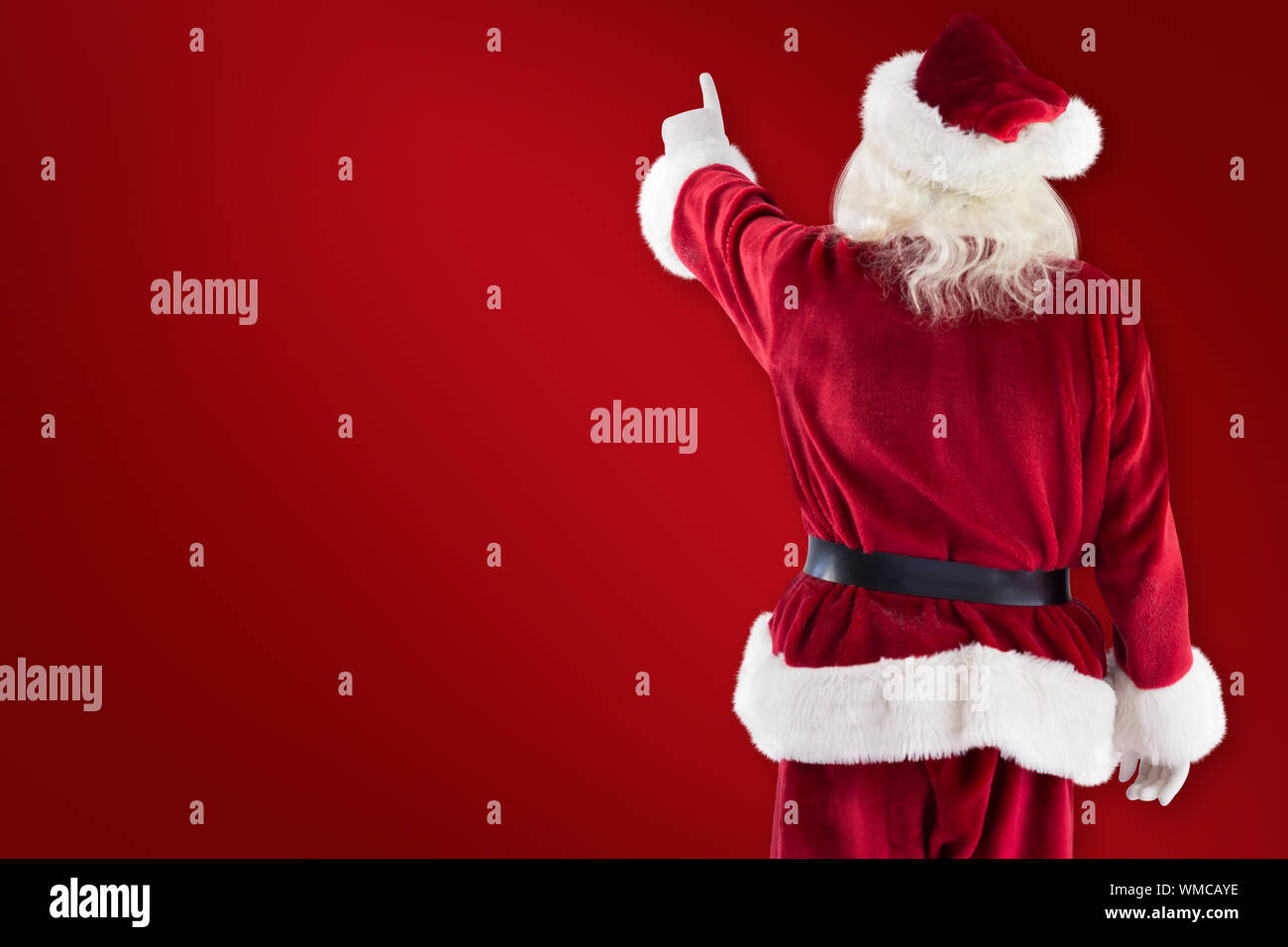 Santa Claus points at something against red background Stock Photo