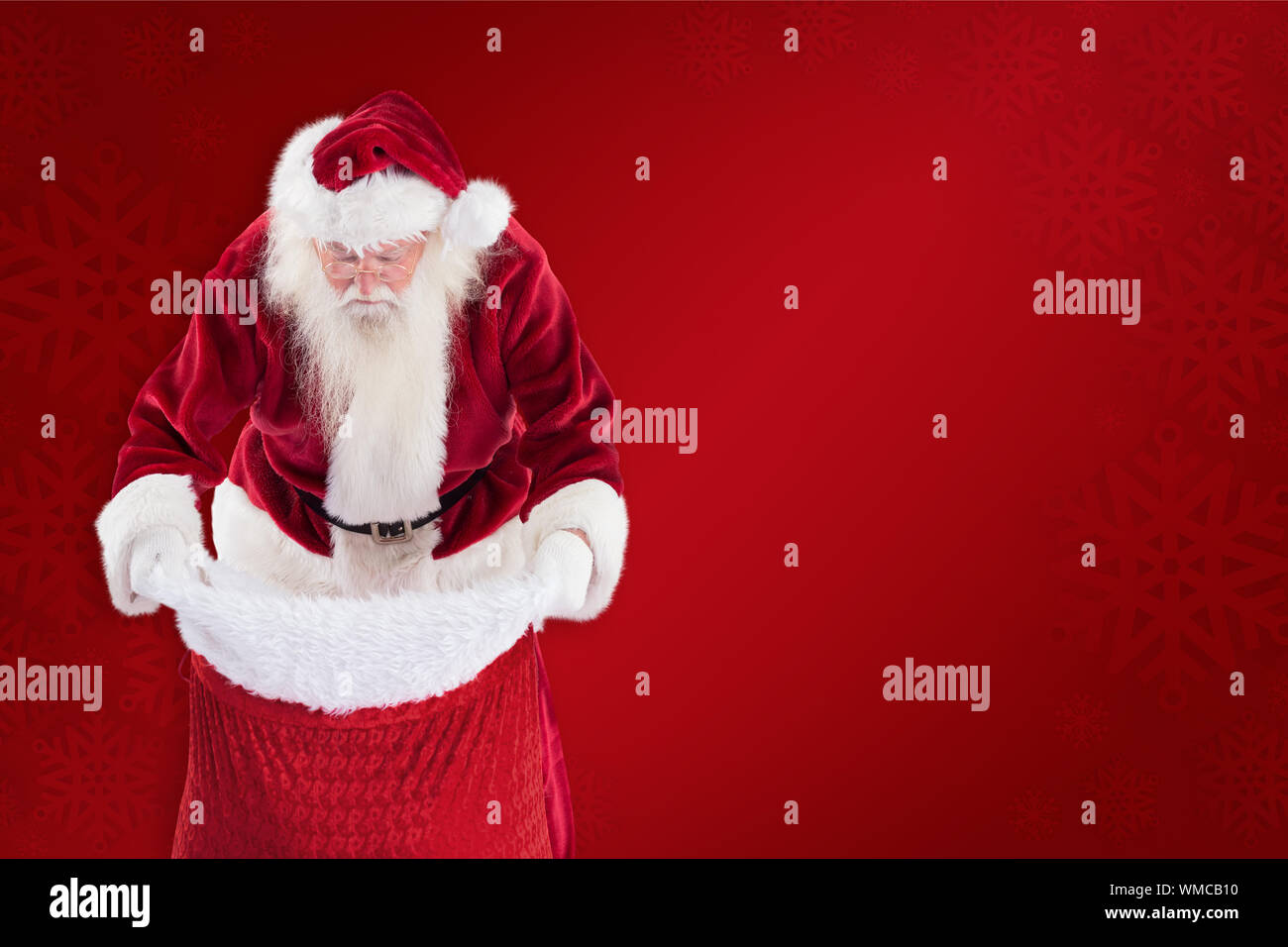 Santa looks in his bag against red background Stock Photo - Alamy