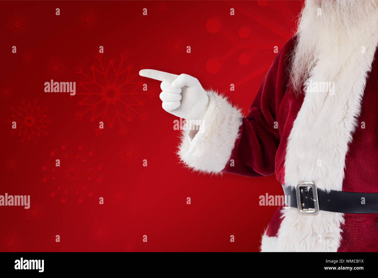 Santa Claus points at something against red background Stock Photo