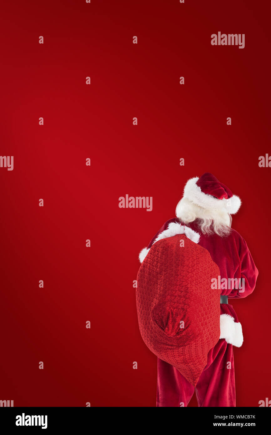 Santa is holding his bag in one hand against red background Stock Photo ...