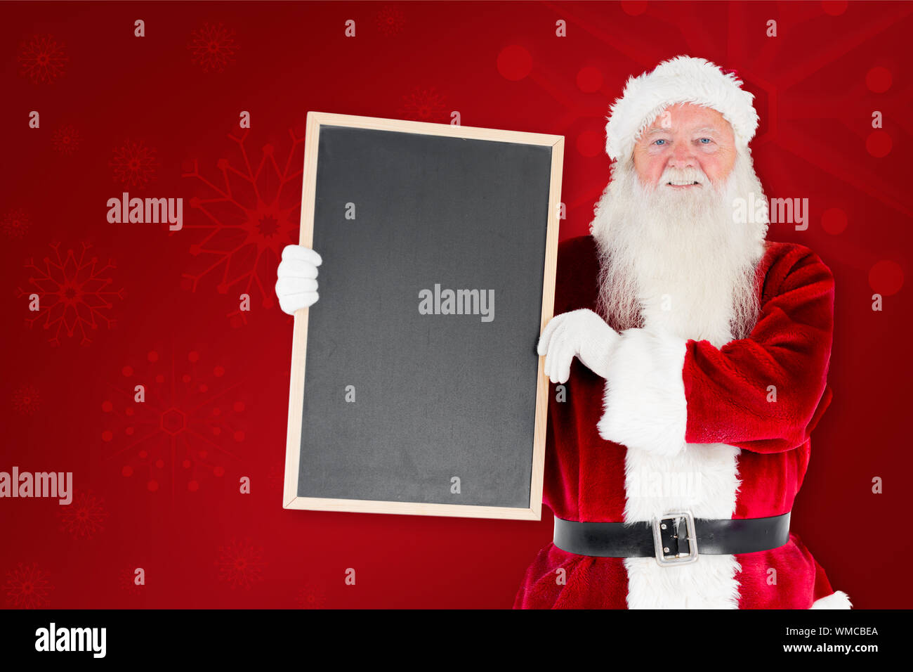 Santa claus showing blackboard against red background Stock Photo - Alamy