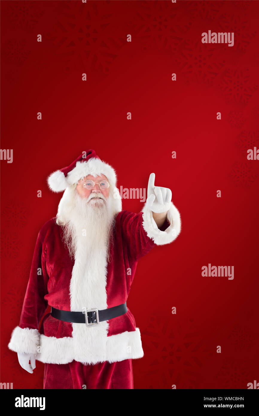 Santa Claus points at something against red background Stock Photo