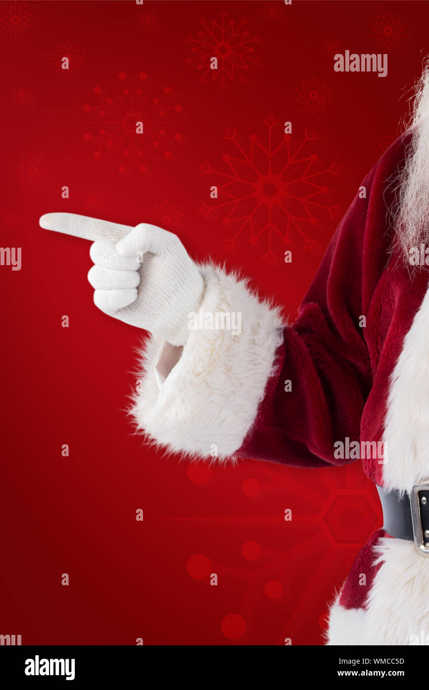 Santa Claus points at something against red background Stock Photo