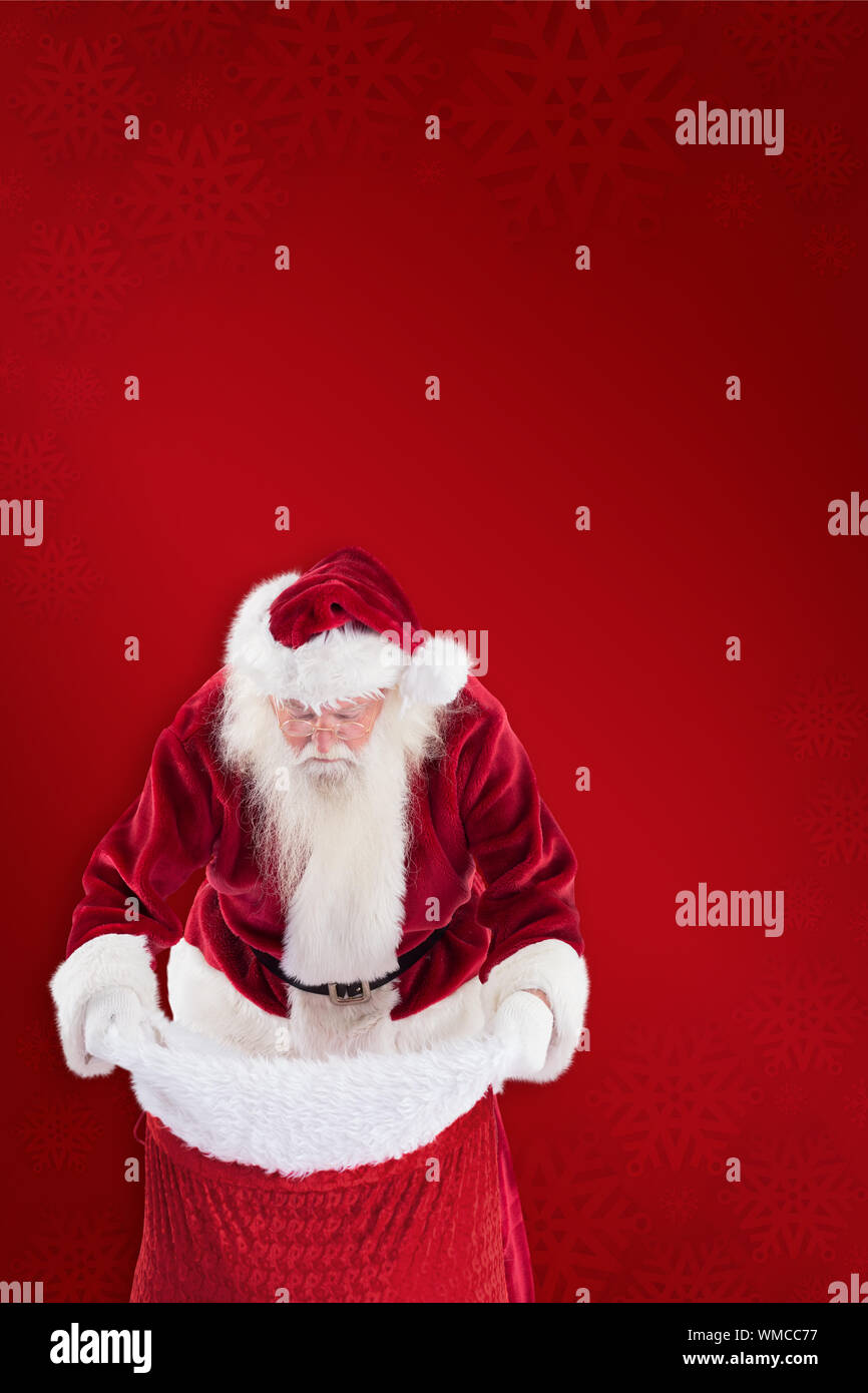 Santa looks in his bag against red background Stock Photo - Alamy