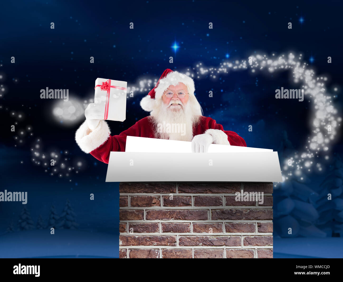 Santa shows a present while holding sign against night sky over forest ...
