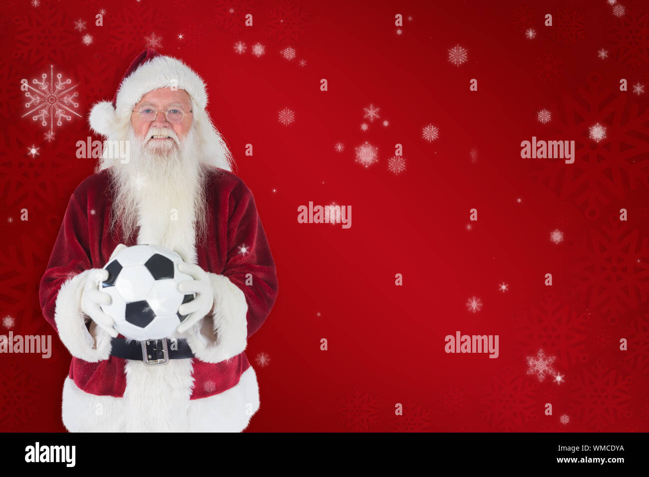 Santa holds a classic football against red snowflake background Stock ...