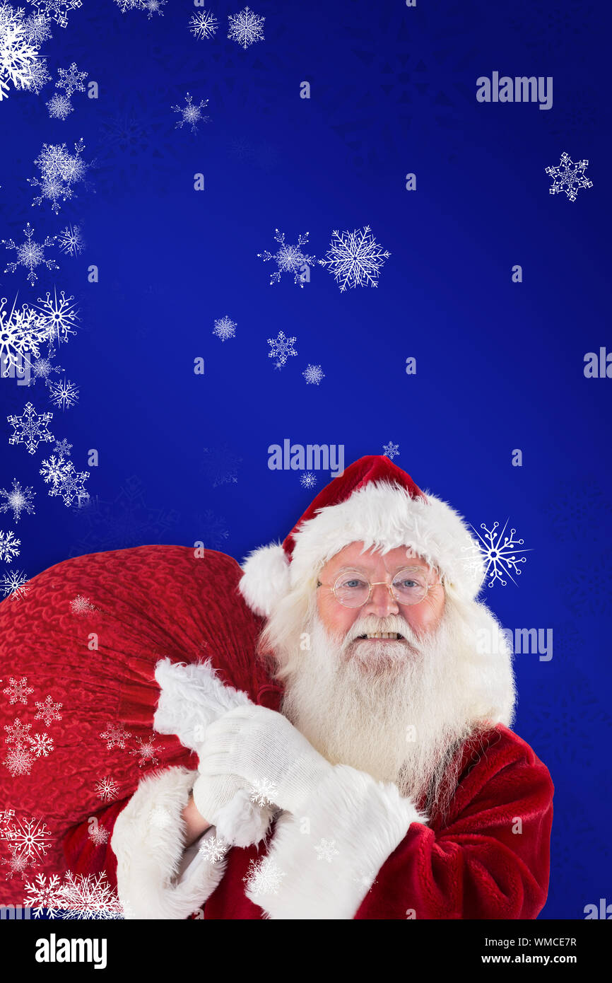 Jolly Santa carries his sack against blue Stock Photo - Alamy