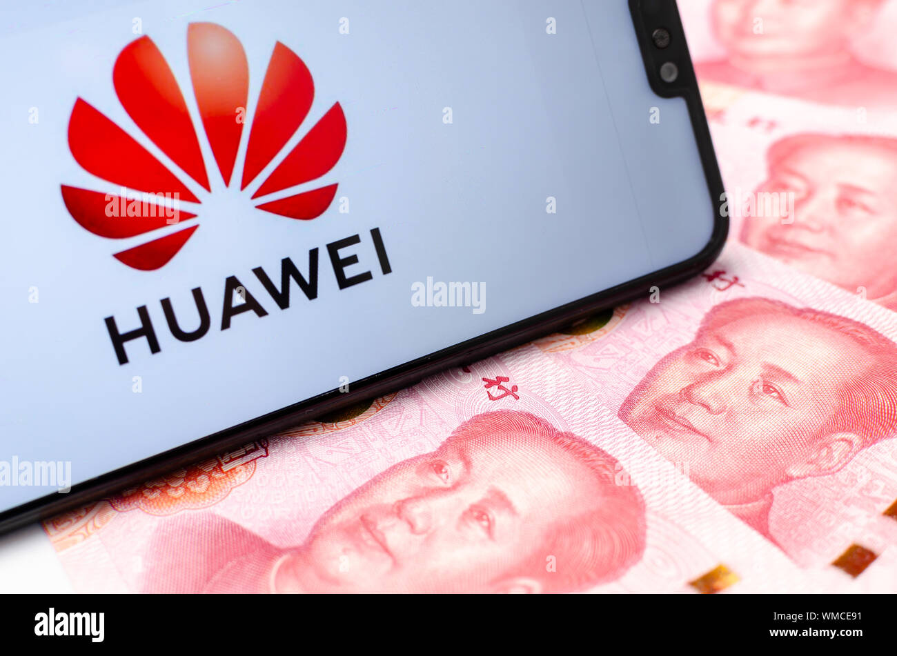 HUAWEI logo on the smartphone which surrounded by the Chinese money - Yuan banknotes. Conceptual photo. Stock Photo