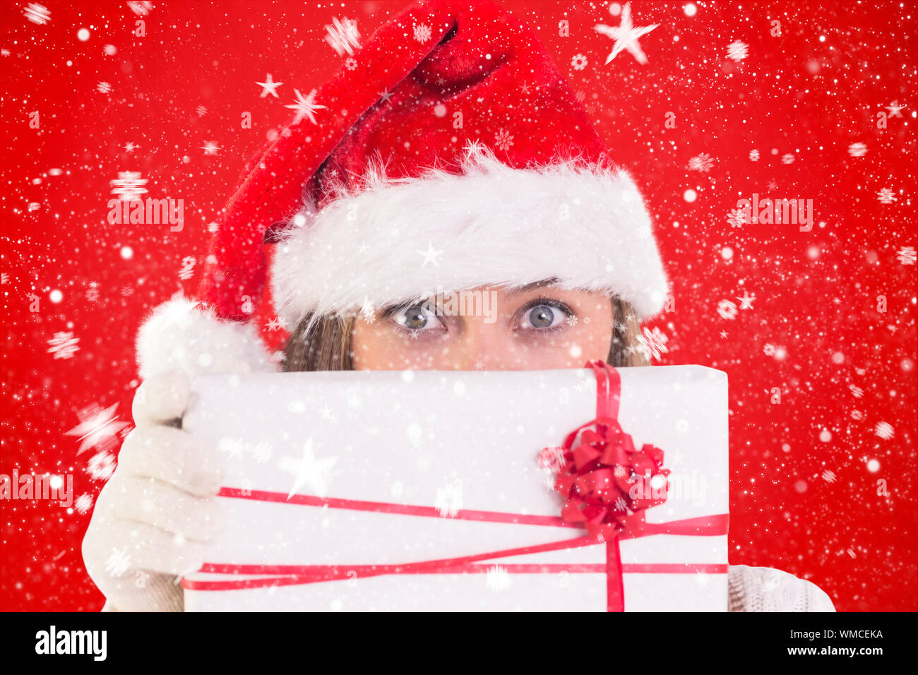 Festive blonde holding a gift against red background Stock Photo - Alamy