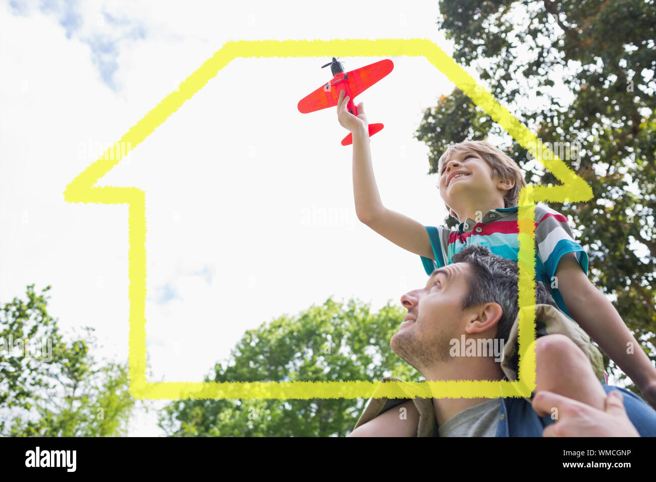 Boy with toy aeroplane sitting on fathers shoulders against house outline Stock Photo