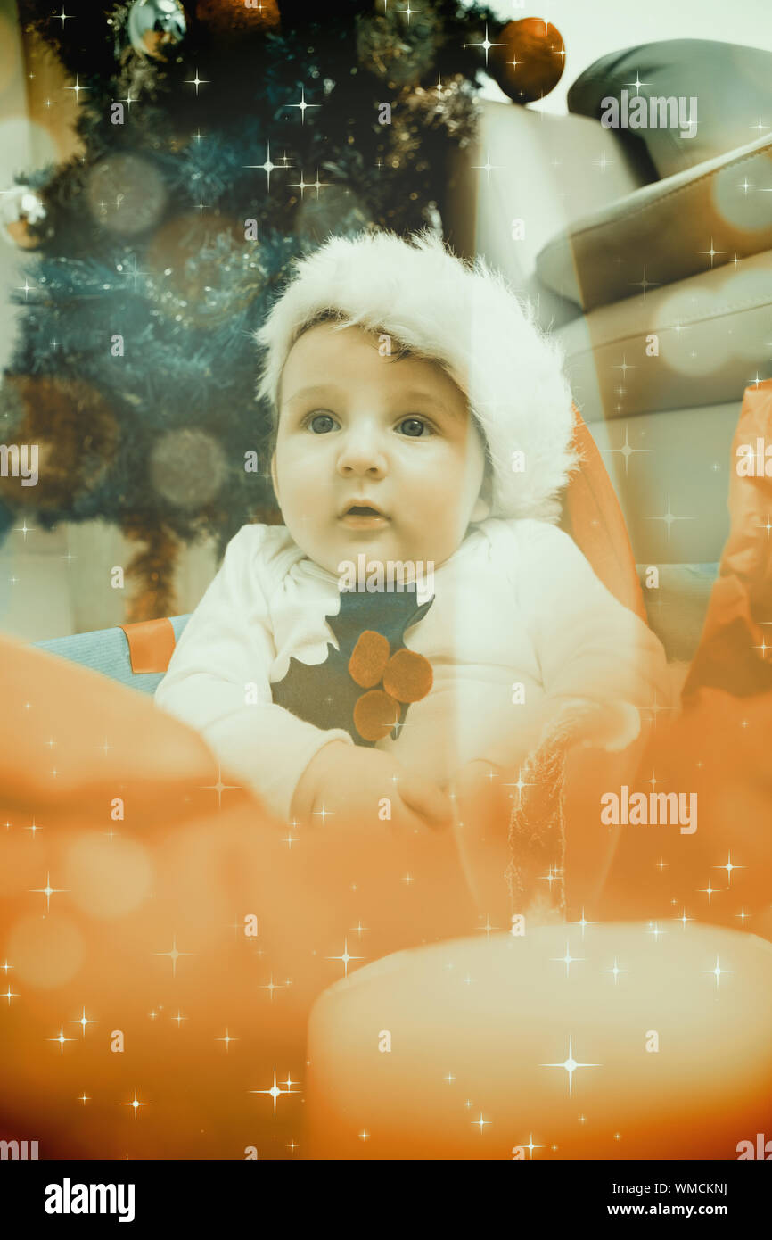 Cute baby boy in large christmas present against candle burning against ...