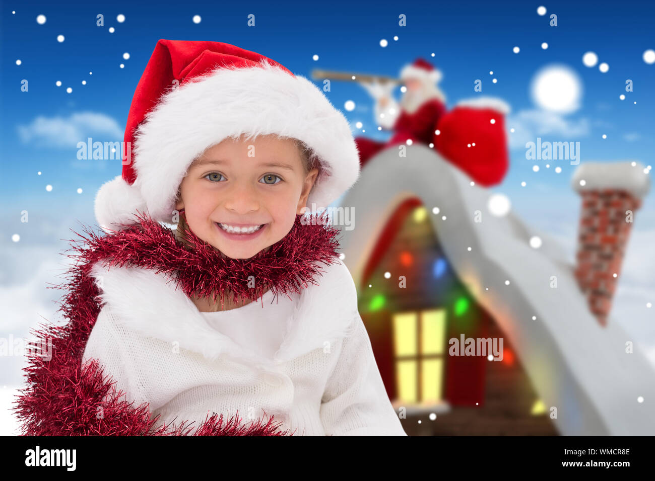 Cute little girl wearing santa hat and tinsel against bright blue sky over clouds Stock Photo