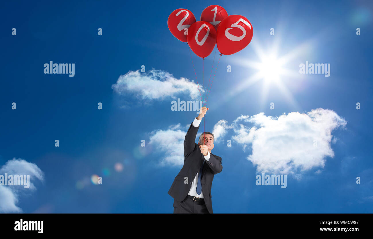 Mature businessman pulling against bright blue sky with clouds Stock ...