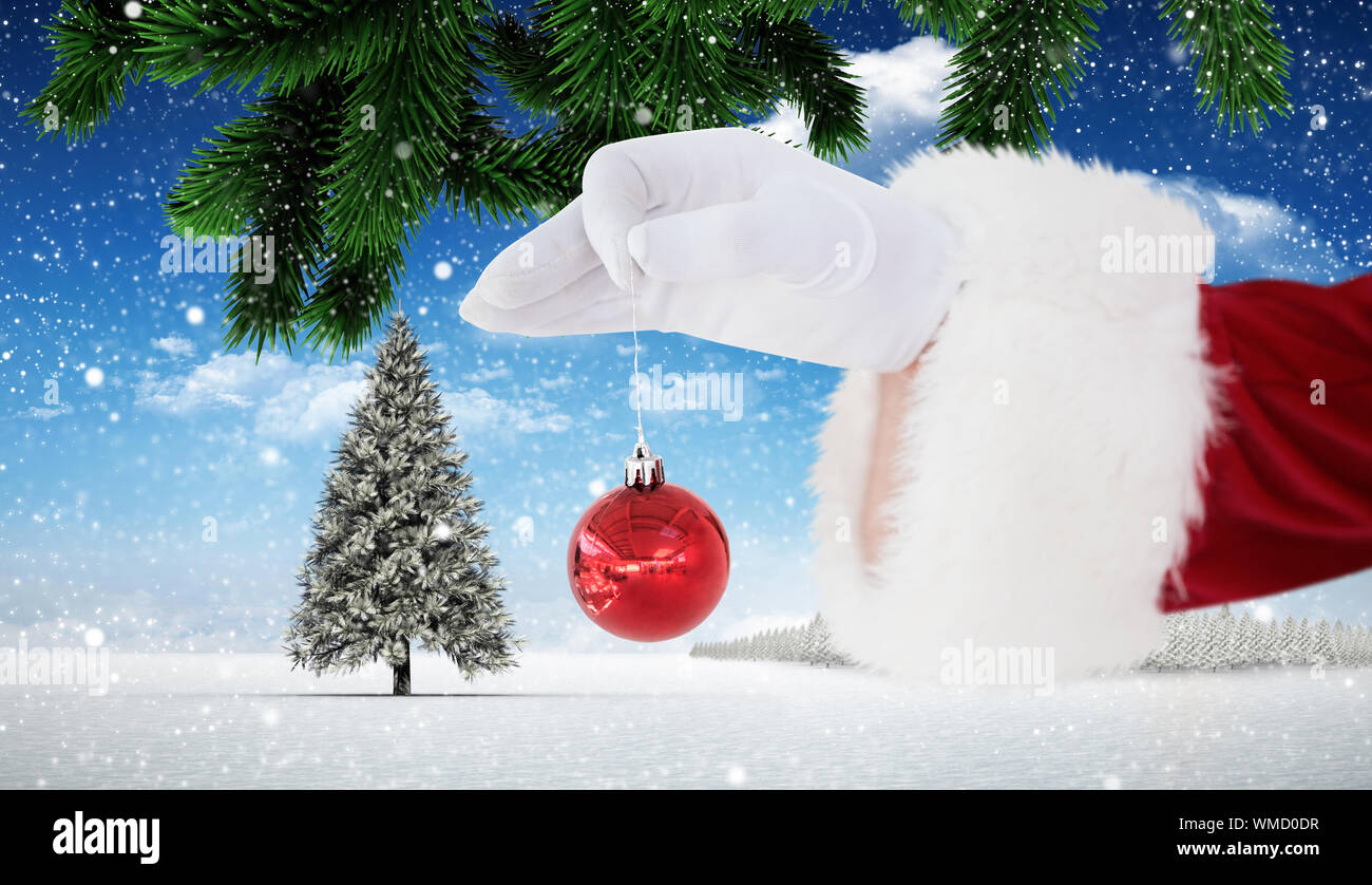 Santa claus holding red bauble against christmas scene Stock Photo