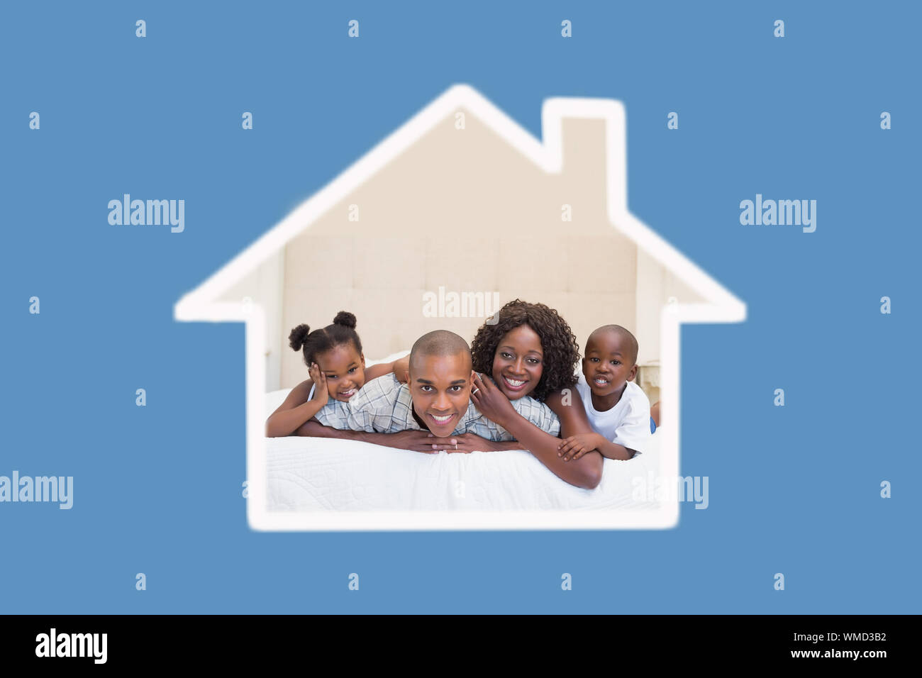 Happy family smiling at camera together on bed against blue background