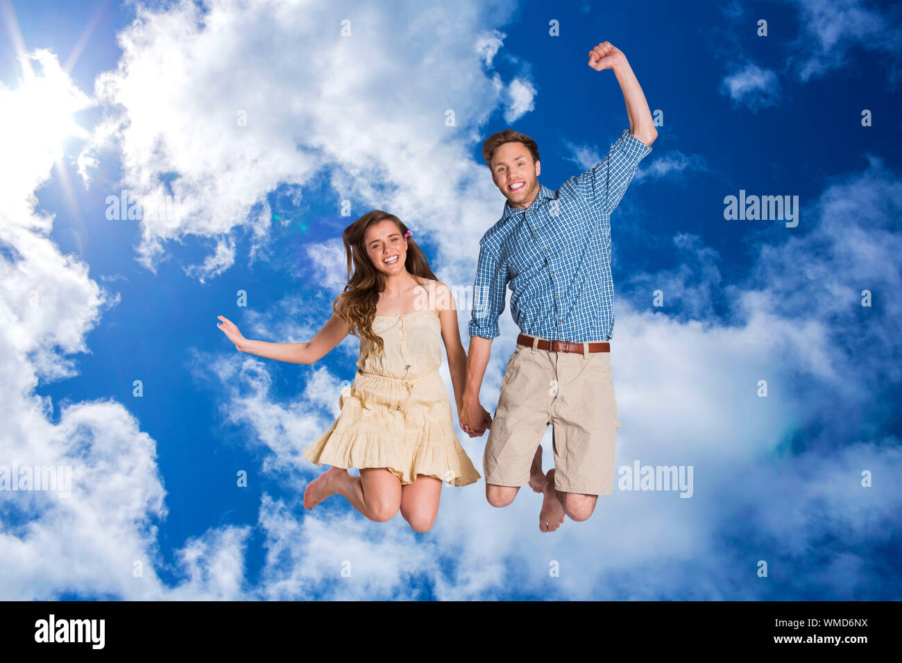 Cheerful young couple jumping against bright blue sky with clouds Stock ...