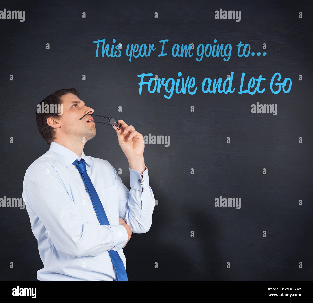 Thinking businessman biting glasses against blackboard Stock Photo